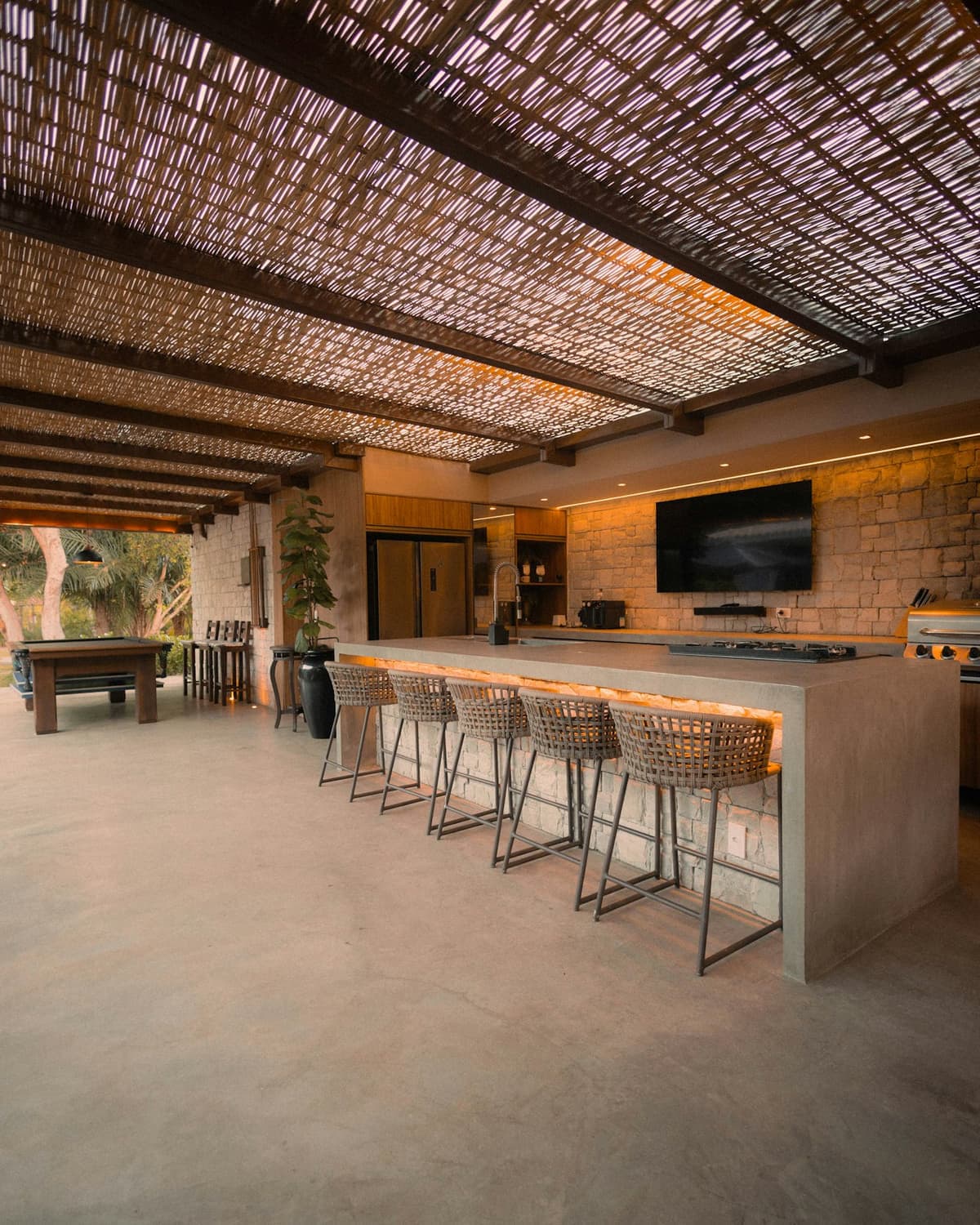 Área gourmet planejada com bancada, banquetas e armários de apoio